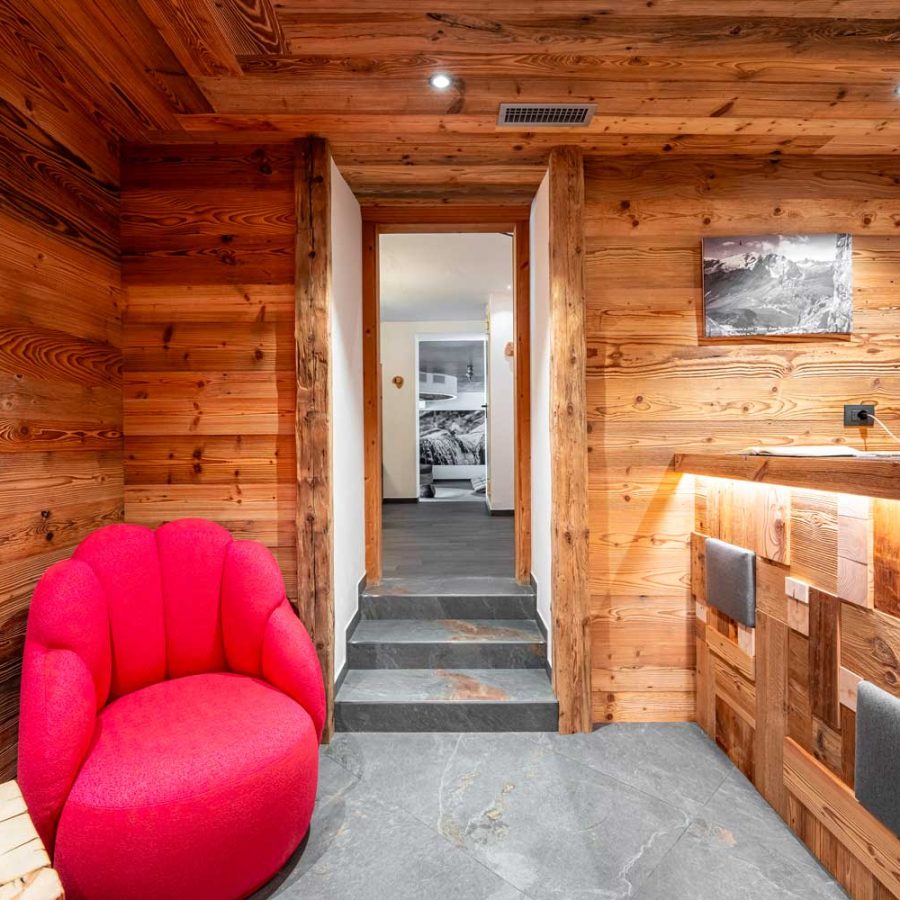 ingresso-spa-hotel-croce-bianca-canazei-con-struttura-in-legno-e-poltrona-rossa