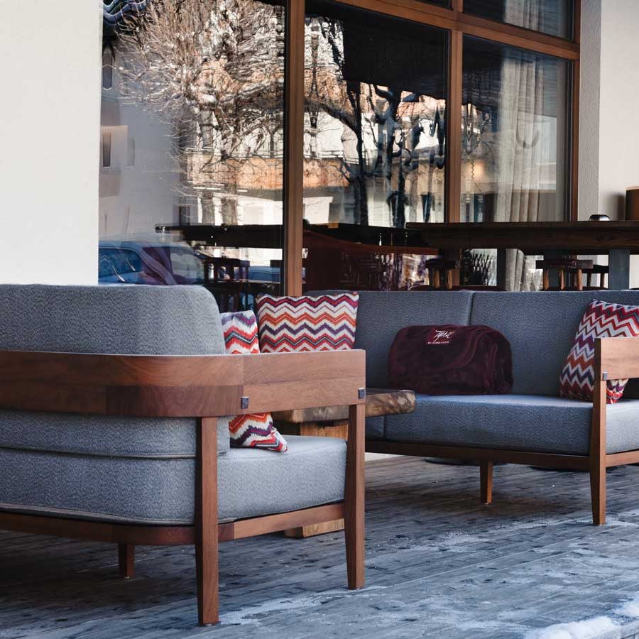 Holz-Sofas und Sessel im Außenbereich auf der Terrasse des Sport Hotel Tyrol in San Candido